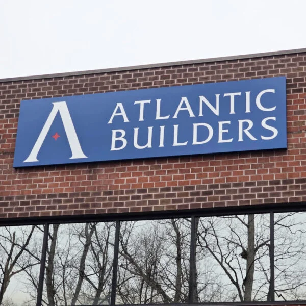 Sign cabinet installed by Distinct Sign Solutions for Atlantic Builders in Fredericksburg, VA. High-contrast branding mounted on brick exterior.