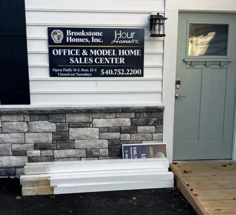 Photo of dark blue, gold, and white aluminum sign affixed to siding at Model Home for Brookstone Homes. Sign was manufactured by Distinct Sign Solutions in Fredericksburg, VA
