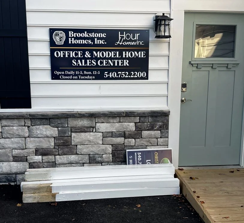 Photo of dark blue, gold, and white aluminum sign affixed to siding at Model Home for Brookstone Homes. Sign was manufactured by Distinct Sign Solutions in Fredericksburg, VA