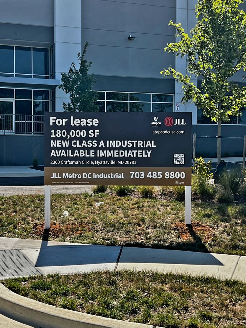 Photo of large post & panel sign affixed to white posts in grassy area. Sign is displaying FOR LEASE for JLL Mid Atlantic in Gaithersburg, MD. Sign was manufactured & installed by Distinct Sign Solutions in Fredericksburg VA