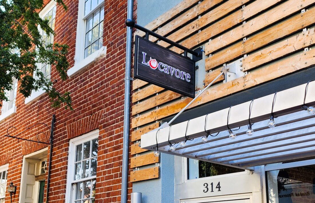 Photo of black powder coated blade sign frame with wooden Locavore printed sign insert. Blade sign is affixed to EIFS building in Downtown Fredericksburg, VA. Sign was manufactured & installed by Distinct Sign Solutions in Fredericksburg, VA