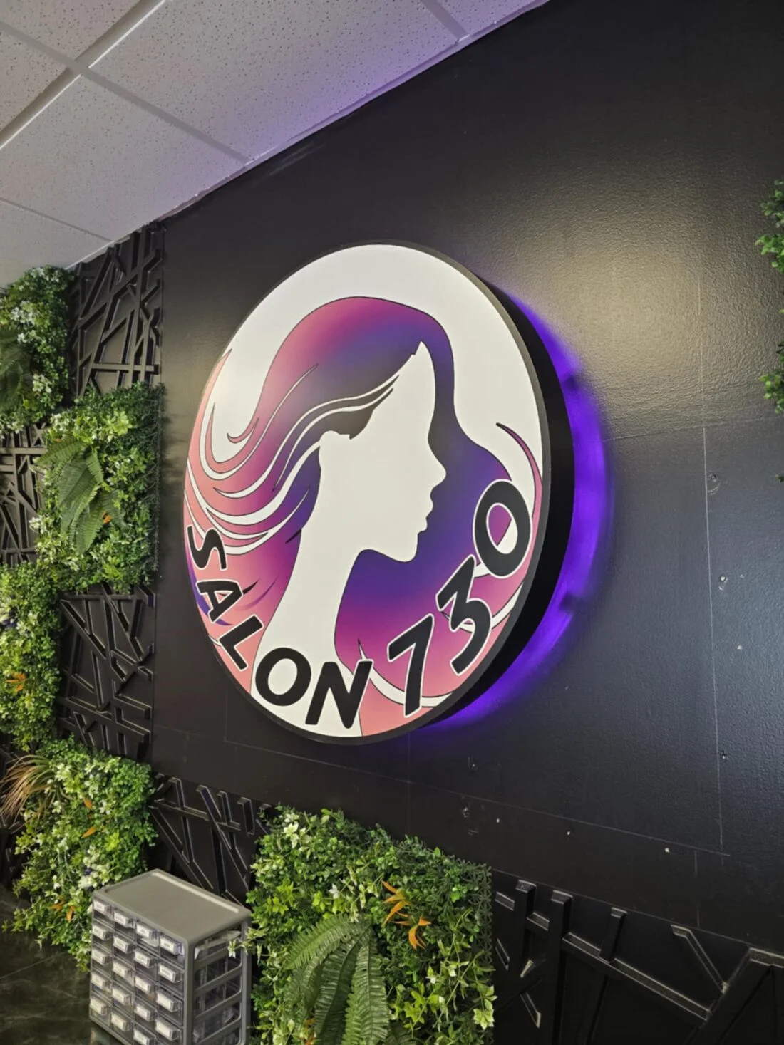 Photo of illuminated wall sign with purple halo lighting against black wall. Sign is for Salon 730, located in Fredericksburg, VA. Sign was manufactured & installed by Distinct Sign Solutions in Fredericksburg, VA