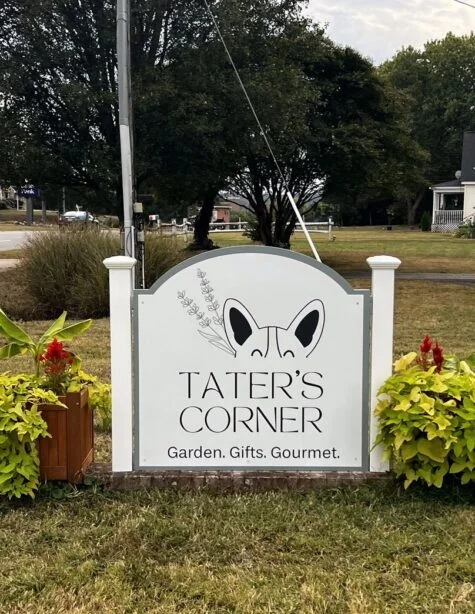 Photo of white and sage green sign with PVC wrapped posts sitting in between floral arrangements in Stafford, VA. Sign was manufactured and installed for Tater's Corner by Distinct Sign Solutions in Fredericksburg, VA