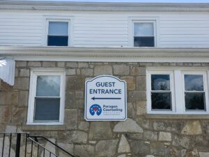 Exterior directional wayfinding sign guiding visitors to a building entrance.